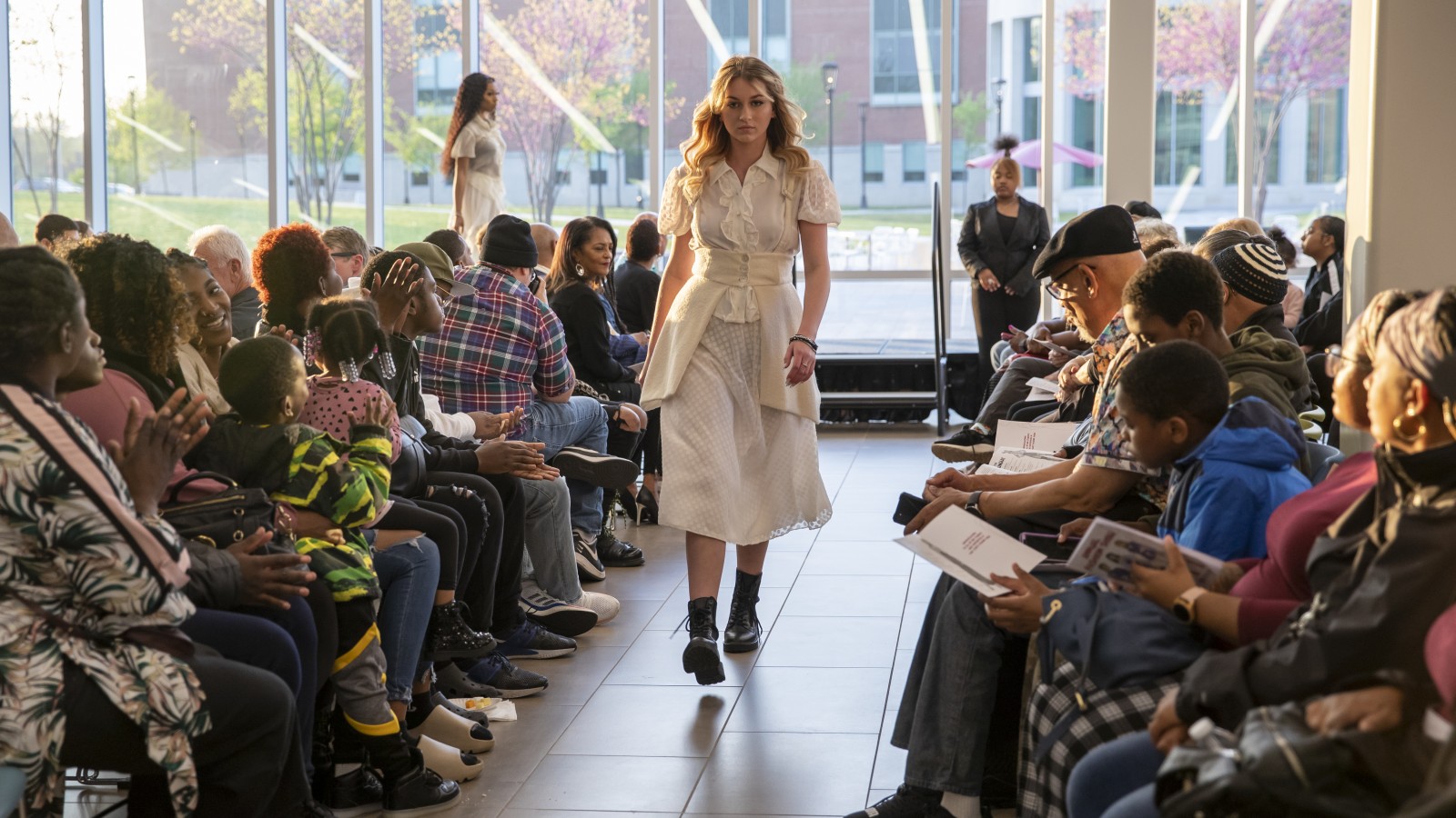 A student wearing white garment and black combat boots at the fashion show