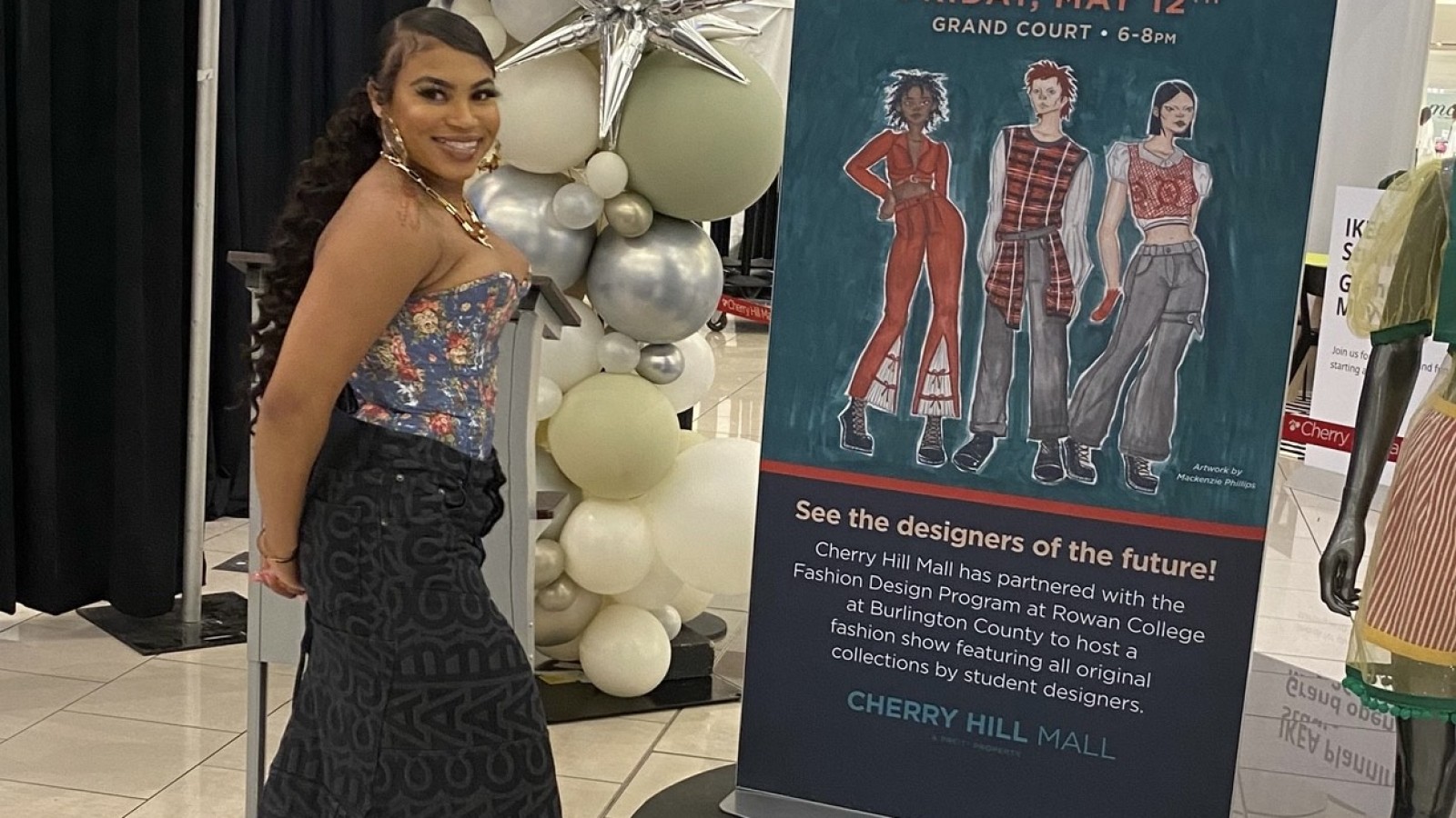 RCBC Fashion design student standing next to Fashion Show poster